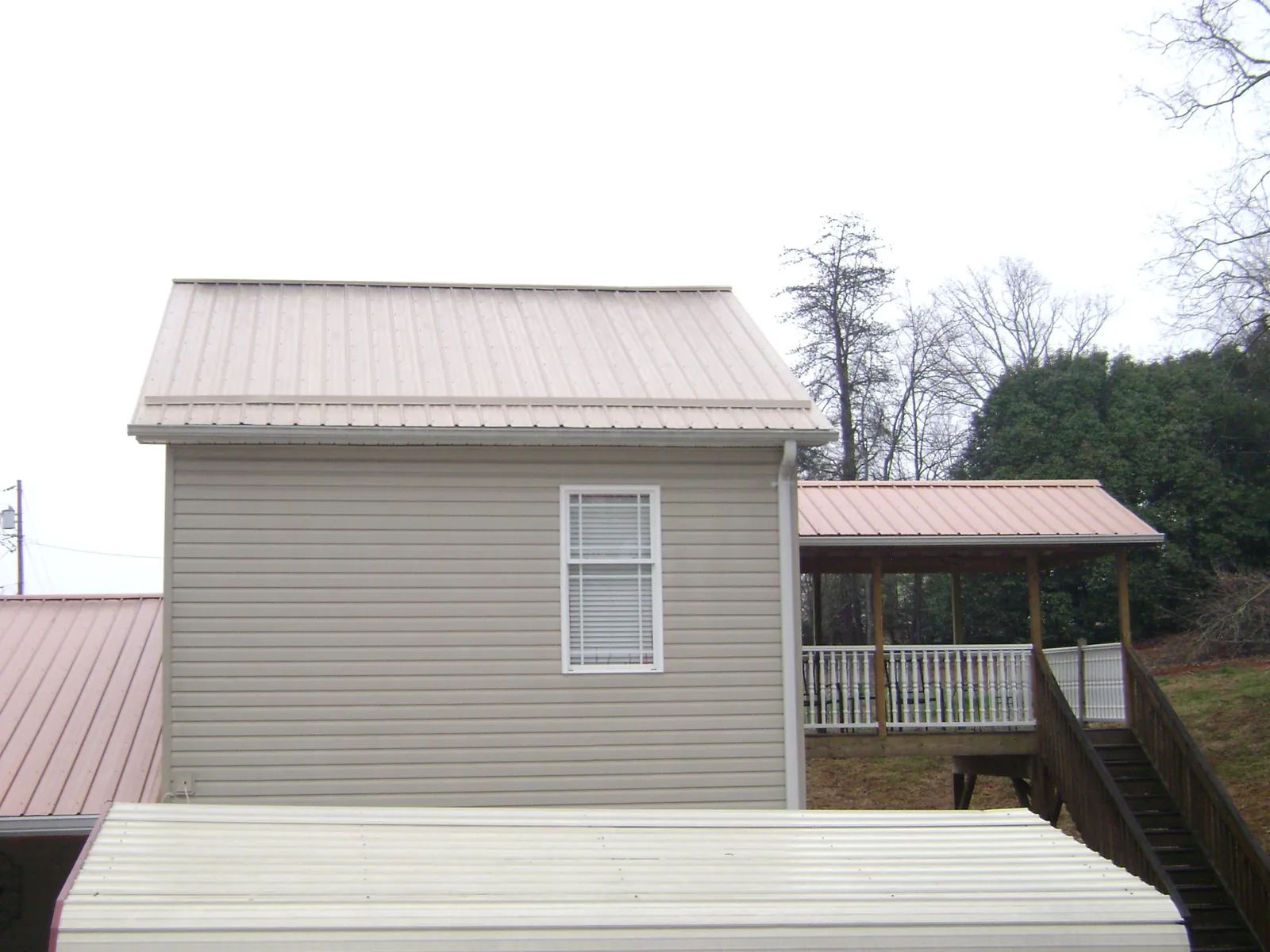 Tan metal roofs on a two story addition and attached porch, from a Roof Replacement job in Quantico